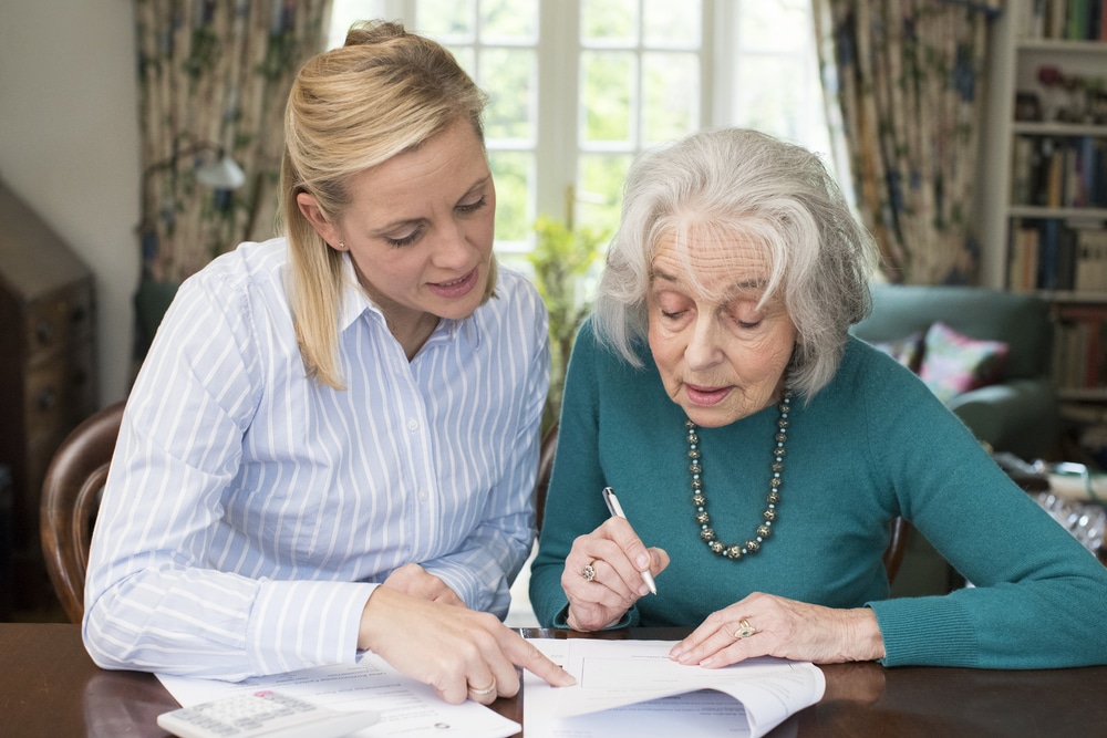 Woman,Helping,Senior,Neighbor,With,Paperwork