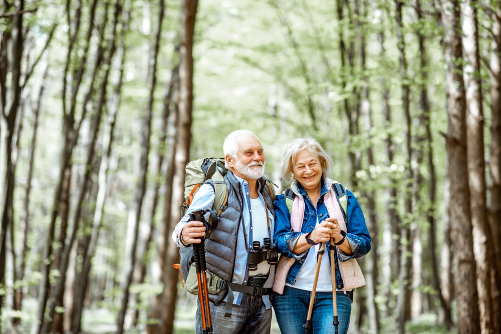 Beautiful,Senior,Couple,Hiking,With,Backpacks,And,Trekking,Sticks,In