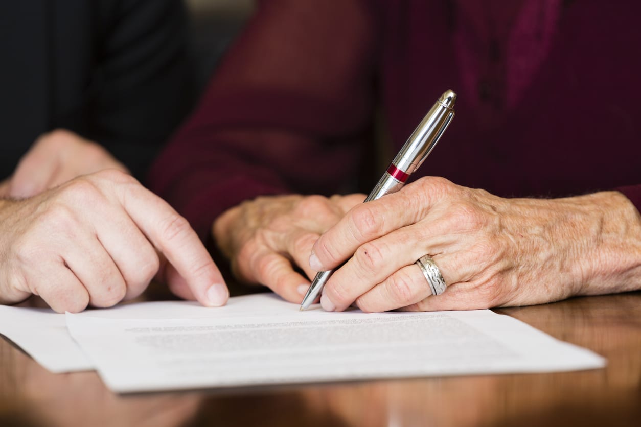 Senior signing guardianship legal documents with family.
