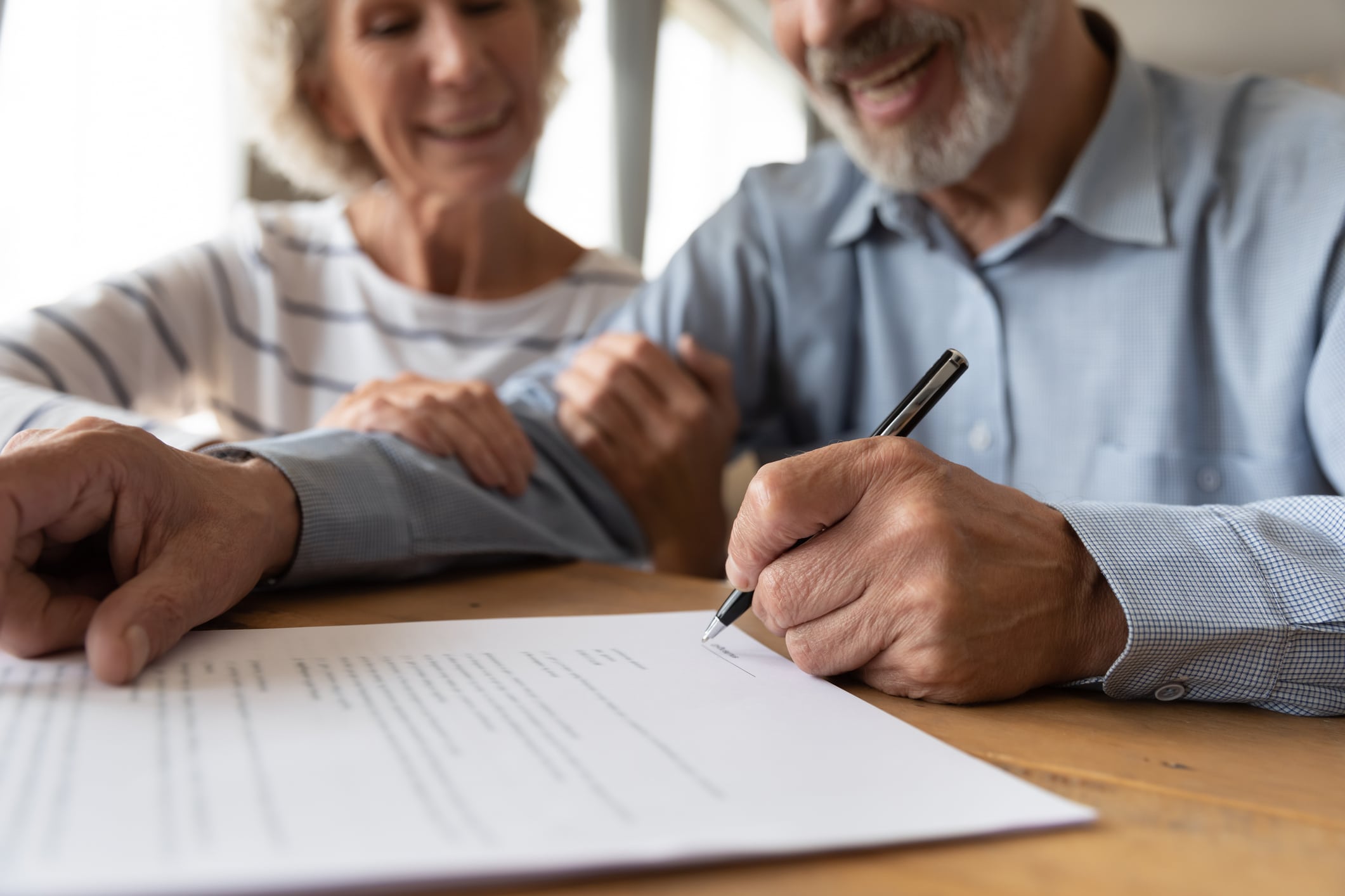Senior couple signing estate planning documents with an attorney.